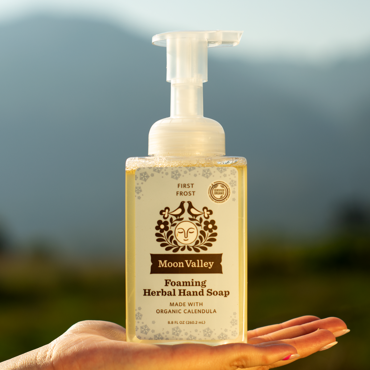 Moon Valley Organics Hand Holding Foaming Herbal Hand Soap Front Dispenser Bottle First Frost